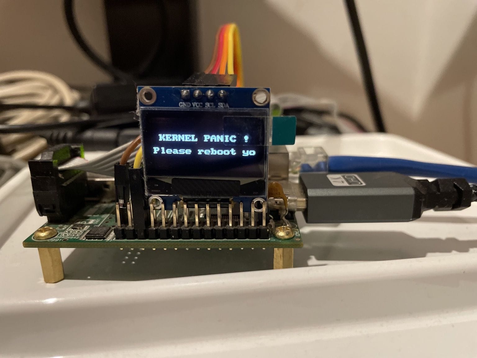 a photo showing off a black drm panic message on a tiny ssd1306 oled display