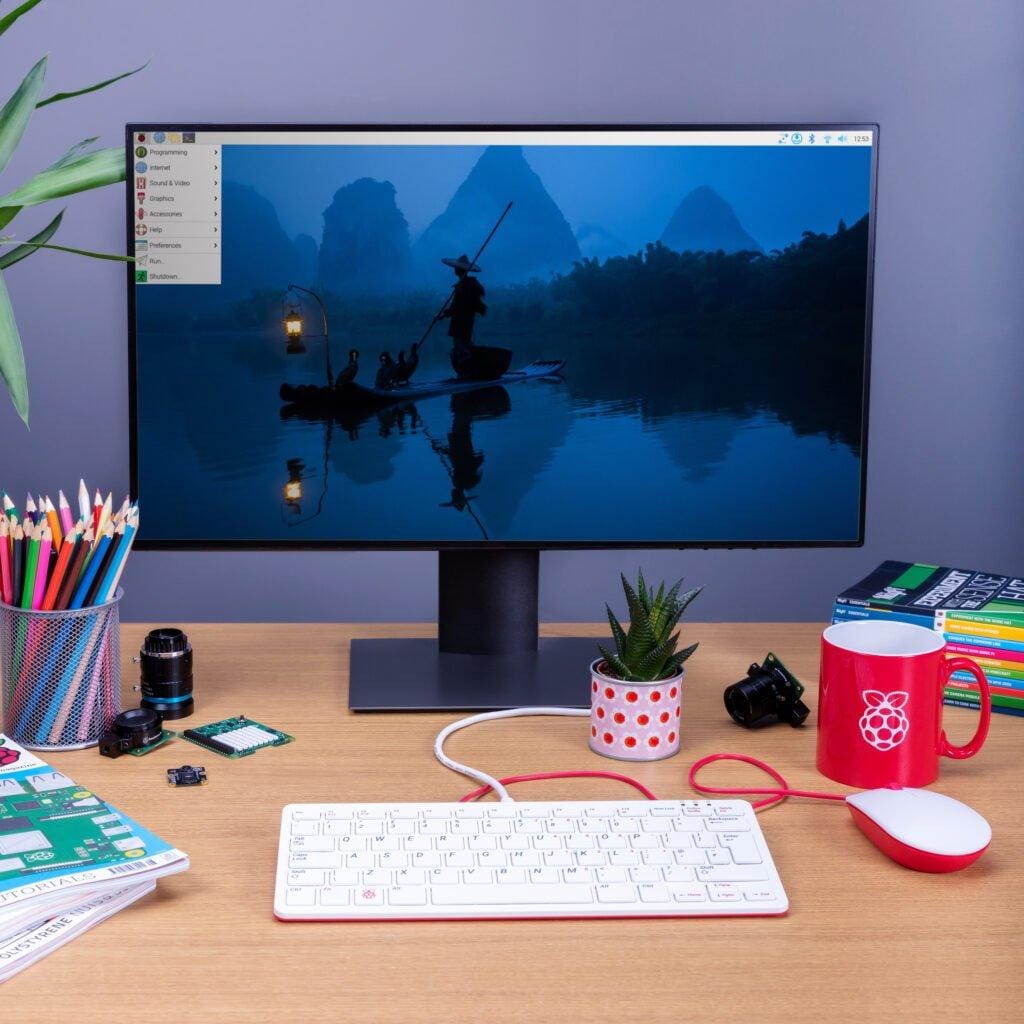 a photo that shows a raspberry pi powered desktop sitting on a table filled with stationery and a keyboard and mouse