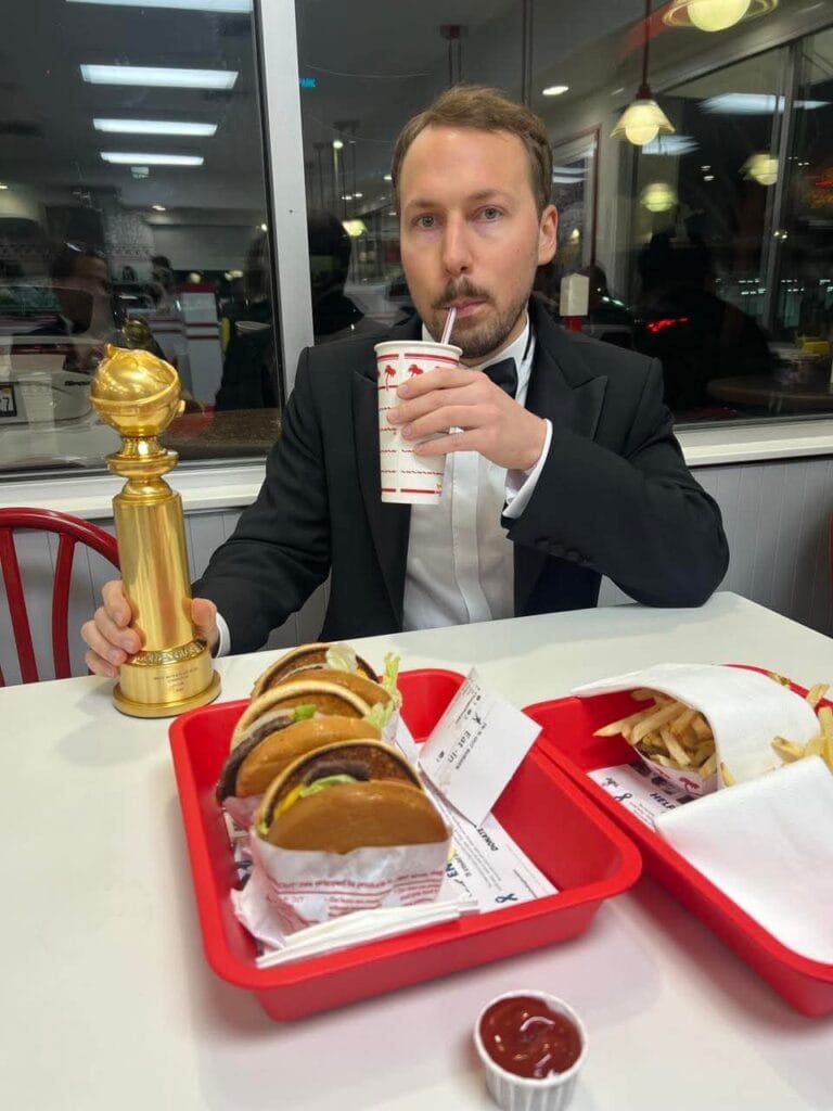 there is a photo of flow director gints zilbalodis having a oscar in one hand and a soft drink in the other